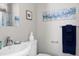 Bright bathroom featuring a sleek white sink, elegant wall art, and coordinated blue accents at 627 New Road, Raleigh, NC 27608