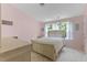 Charming bedroom with pink walls, carpet, a queen-size bed, and natural light from a bank of windows at 7856 Spungold St, Raleigh, NC 27617