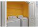 Laundry room with a side-by-side washer and dryer set, wire shelving and bright yellow walls at 7856 Spungold St, Raleigh, NC 27617