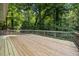 Large back deck with wooden railing offering serene view of surrounding lush, green trees at 7916 Foxwood Dr, Raleigh, NC 27615