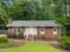 Inviting single-story brick home with a green lawn and landscaped garden area, perfect for outdoor enjoyment at 7916 Foxwood Dr, Raleigh, NC 27615