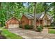 Brick home with attached garage and driveway, surrounded by mature trees and lush greenery at 101 Turnberry Ln, Cary, NC 27511