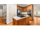 Kitchen with island cooktop, refrigerator, built-in ovens, wood cabinetry, and hardwood flooring at 101 Turnberry Ln, Cary, NC 27511