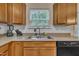 Kitchen sink area featuring wood cabinets, neutral countertops, and a window overlooking trees at 111 S Rose Hill Dr, Clayton, NC 27520