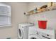 Laundry room featuring a window, two laundry machines, and a storage rack at 111 S Rose Hill Dr, Clayton, NC 27520