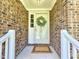 Covered front porch with brick walls and storm door decorated with a wreath for a welcoming touch at 112 Saddletree Rd, Oxford, NC 27565