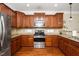 Well-lit kitchen with wood floors, stainless steel appliances, granite countertops, and wood cabinets at 11612 Leesville Rd, Raleigh, NC 27613