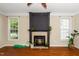 Cozy living room featuring a fireplace with decorative mantel, large windows, and hardwood floors at 11612 Leesville Rd, Raleigh, NC 27613