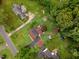 Aerial view showcasing the property with a large yard, driveway, and multiple outbuildings, surrounded by trees at 132 Lord Ashley Rd, Raleigh, NC 27610