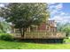Exterior view of a backyard deck and a house with large trees and a green lawn at 132 Lord Ashley Rd, Raleigh, NC 27610