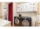 Convenient laundry room equipped with a washer and dryer with white cabinets and red curtain at 132 Lord Ashley Rd, Raleigh, NC 27610