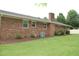 Brick home exterior featuring a green lawn, mulch beds, air conditioning unit, and a brick chimney at 1418 Sherron Rd, Durham, NC 27703