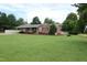 Charming brick ranch-style home with mature trees, lush green lawn, and convenient carport at 1418 Sherron Rd, Durham, NC 27703