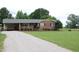 Charming brick home with a well-maintained lawn, a gravel driveway, and mature trees, offering inviting curb appeal at 1418 Sherron Rd, Durham, NC 27703