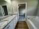 Well-lit bathroom features dual sinks with granite countertop, soaking tub and view to bedroom at 168 Oakfield Trace Dr, Four Oaks, NC 27524