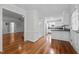 Bright kitchen featuring white cabinets, hardwood floors, and an open layout with a view into the living area at 211 Forestview Dr, Elon, NC 27244