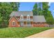 Charming brick two-story home with lush lawn, mature trees and a welcoming front porch at 213 Brompton Ct, Burlington, NC 27215