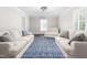 Bright living room features a blue rug, white sofas, and shuttered windows at 213 Brompton Ct, Burlington, NC 27215