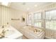 Bathroom featuring a garden tub, double sinks, brass fixtures, and natural light at 322 Gravley Dr, Rocky Mount, NC 27804