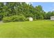 Expansive backyard featuring lush green grass and mature trees, shed, and a storage building at 34 Scotts Creek Run, Angier, NC 27501