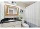 Bathroom vanity with a dark granite countertop, decorative mirror, and nearby toilet with shower behind at 3421 Kistler Ct, Willow Springs, NC 27592