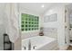 Bright bathroom featuring a large soaking tub beneath a glass block window for natural light and privacy at 3421 Kistler Ct, Willow Springs, NC 27592