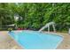 Aerial view of a fenced swimming pool with sunshades, chairs, and a slide in a wooded backyard at 3421 Kistler Ct, Willow Springs, NC 27592