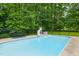 Swimming pool in fenced backyard surrounded by trees, slide, and table with chairs at 3421 Kistler Ct, Willow Springs, NC 27592