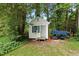 Backyard shed with blue shutters and a small porch, set among trees and landscaping at 3421 Kistler Ct, Willow Springs, NC 27592