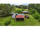 Aerial view reveals multiple outbuildings and carports on green land surrounded by trees at 4053 Friendship Patterson Mill Road, Burlington, NC 27215