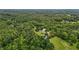 Aerial view reveals a picturesque house nestled amid dense trees and expansive, verdant fields at 4053 Friendship Patterson Mill Road, Burlington, NC 27215