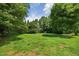 A spacious backyard featuring lush green grass and mature trees providing ample shade and privacy at 4067 Williams Mill Rd, Burlington, NC 27215