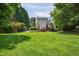 Expansive backyard with lush green lawn, mature trees, and house with a blue metal roof, wooden deck at 4067 Williams Mill Rd, Burlington, NC 27215