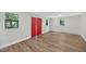 Spacious room features wood-look flooring, multiple windows, and a striking red door, ideal for versatile use at 4067 Williams Mill Rd, Burlington, NC 27215