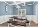Well-lit dining room boasts a rustic table and bench seating beneath a modern chandelier and a large window at 414 Fallingbrook Dr, Kenly, NC 27542