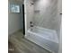 Bathroom featuring a soaking tub with marble tile surround and a small window at 4511 Denfield St, Durham, NC 27704
