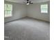 Bright bedroom with neutral carpet, ceiling fan, and two windows offering natural light at 4511 Denfield St, Durham, NC 27704