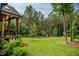 Expansive, well-manicured lawn with mature trees, a charming playhouse, and a glimpse of the home's exterior at 46 Lakes Edge Ln, Pittsboro, NC 27312