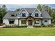 Inviting front facade of a modern farmhouse featuring a well-maintained lawn and covered entry at 46 Lakes Edge Ln, Pittsboro, NC 27312