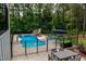 Backyard pool area featuring a pool with slide, a table with chairs, and lounge chairs surrounded by lush trees at 46 Lakes Edge Ln, Pittsboro, NC 27312