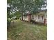 Exterior view of the house with a large tree, a porch with chairs, and overgrown yard at 505 S 15Th St, Erwin, NC 28339