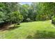 Green backyard featuring an open lawn area surrounded by mature trees and landscaping at 512 Belmont Cir, Wake Forest, NC 27587