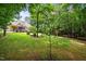 Scenic backyard with green grass, mature trees, and the rear of the home with a screened porch at 512 Belmont Cir, Wake Forest, NC 27587