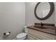 Half bathroom with a toilet, brown granite sink and round mirror on a light grey wall at 512 Belmont Cir, Wake Forest, NC 27587