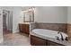 Bathroom featuring a soaking tub, wood cabinets, granite countertops, and modern fixtures at 512 Belmont Cir, Wake Forest, NC 27587