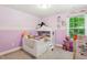 Charming bedroom featuring a unique bed frame, soft purple walls, and a window providing natural light and outdoor views at 6102 Burning Tree Cir, Sanford, NC 27332