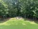A beautiful backyard featuring a circular paved fire pit surrounded by bench seating and mature trees at 7008 Rex, Holly Springs, NC 27540