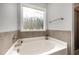 Relaxing bathroom featuring a soaking tub with tile surround, a decorative window, and neutral decor at 71 Sanibel St, Clayton, NC 27520
