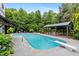 Gorgeous in-ground pool featuring a diving board and covered deck with seating, perfect for outdoor enjoyment at 7132 Deer Brook St, Willow Springs, NC 27592