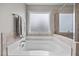 Soaking tub under patterned window with chrome hardware and tile surround at 81 Dot Ct, Fuquay Varina, NC 27526